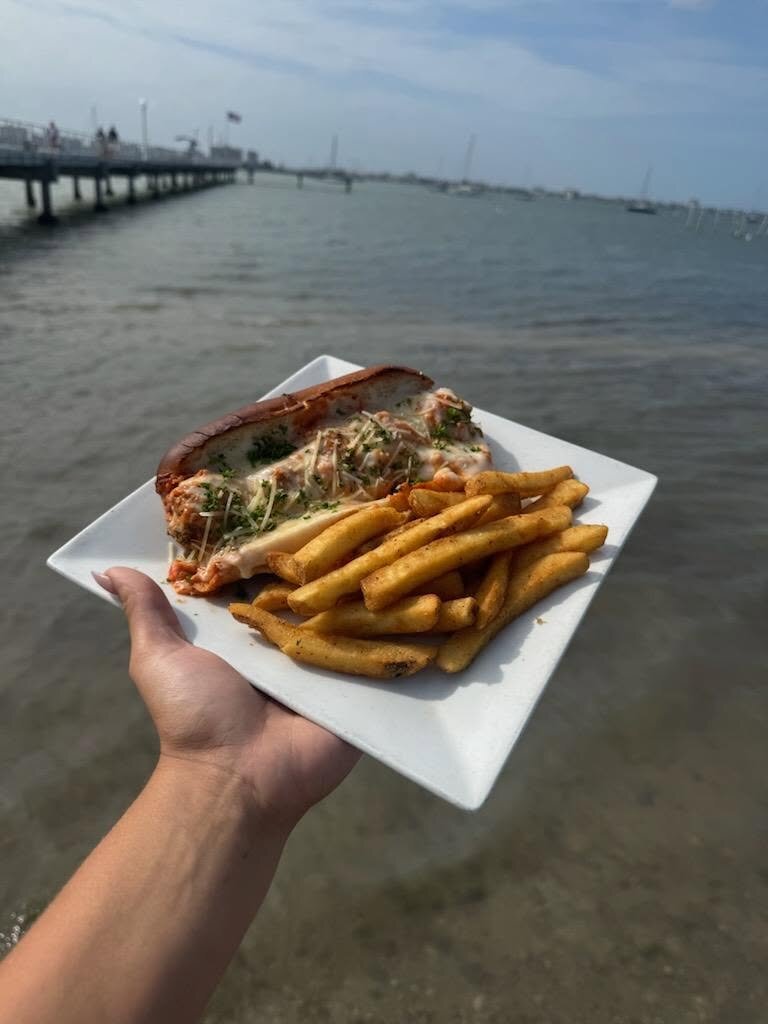 A hand holding a plate out over the bay at O'Maddy's