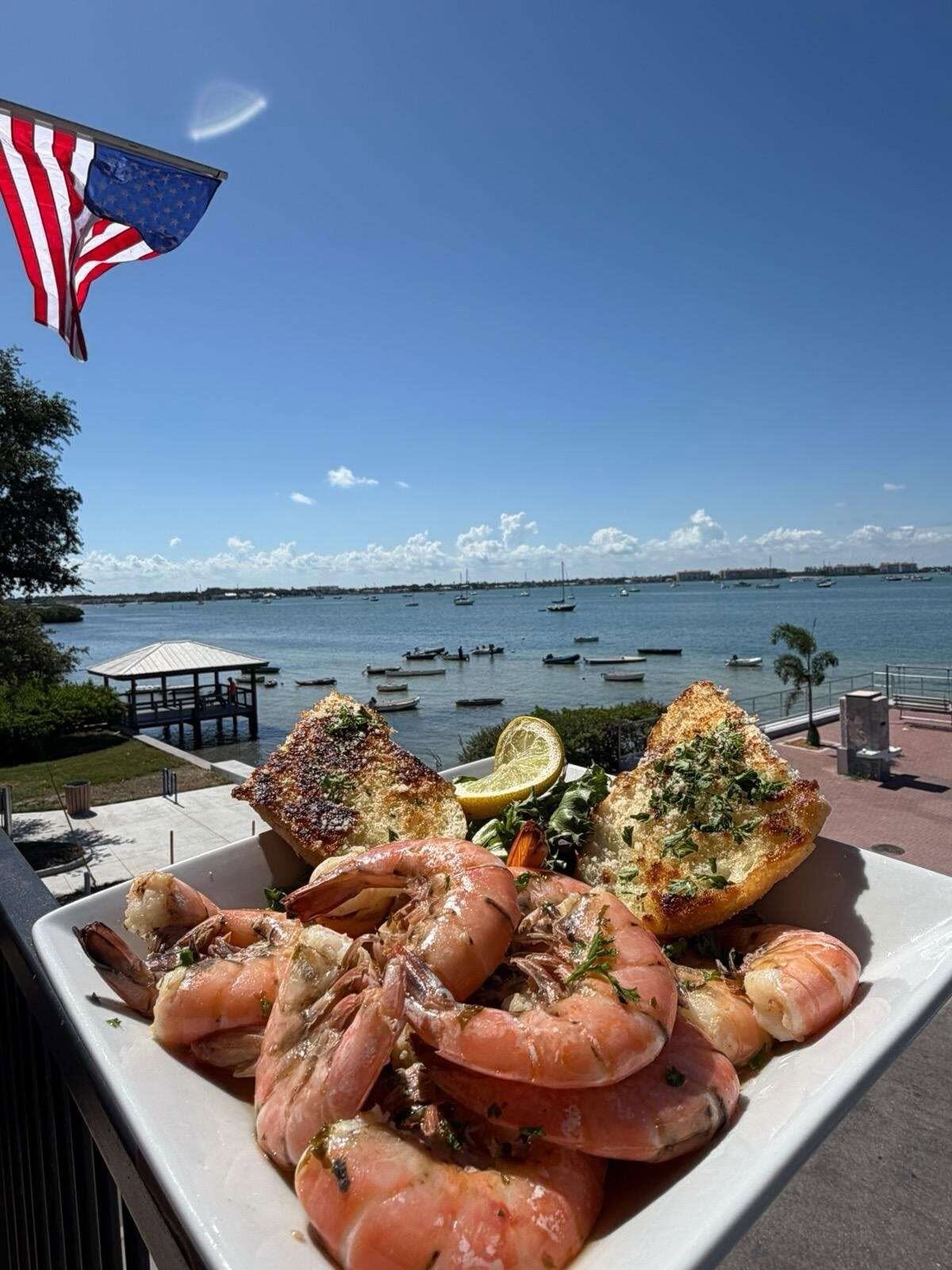 A shrimp plate on O'Maddy's covered upper deck over the bay, flag and boats in frame