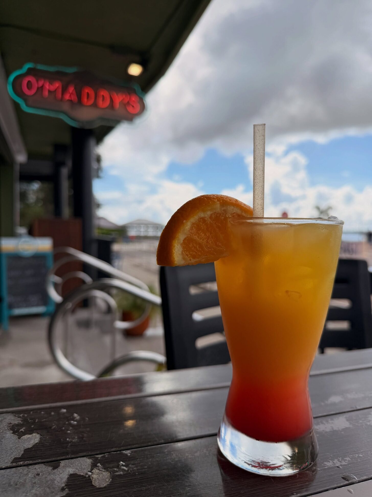 A tequila sunrise at the O’Maddy’s bar with the neon sign