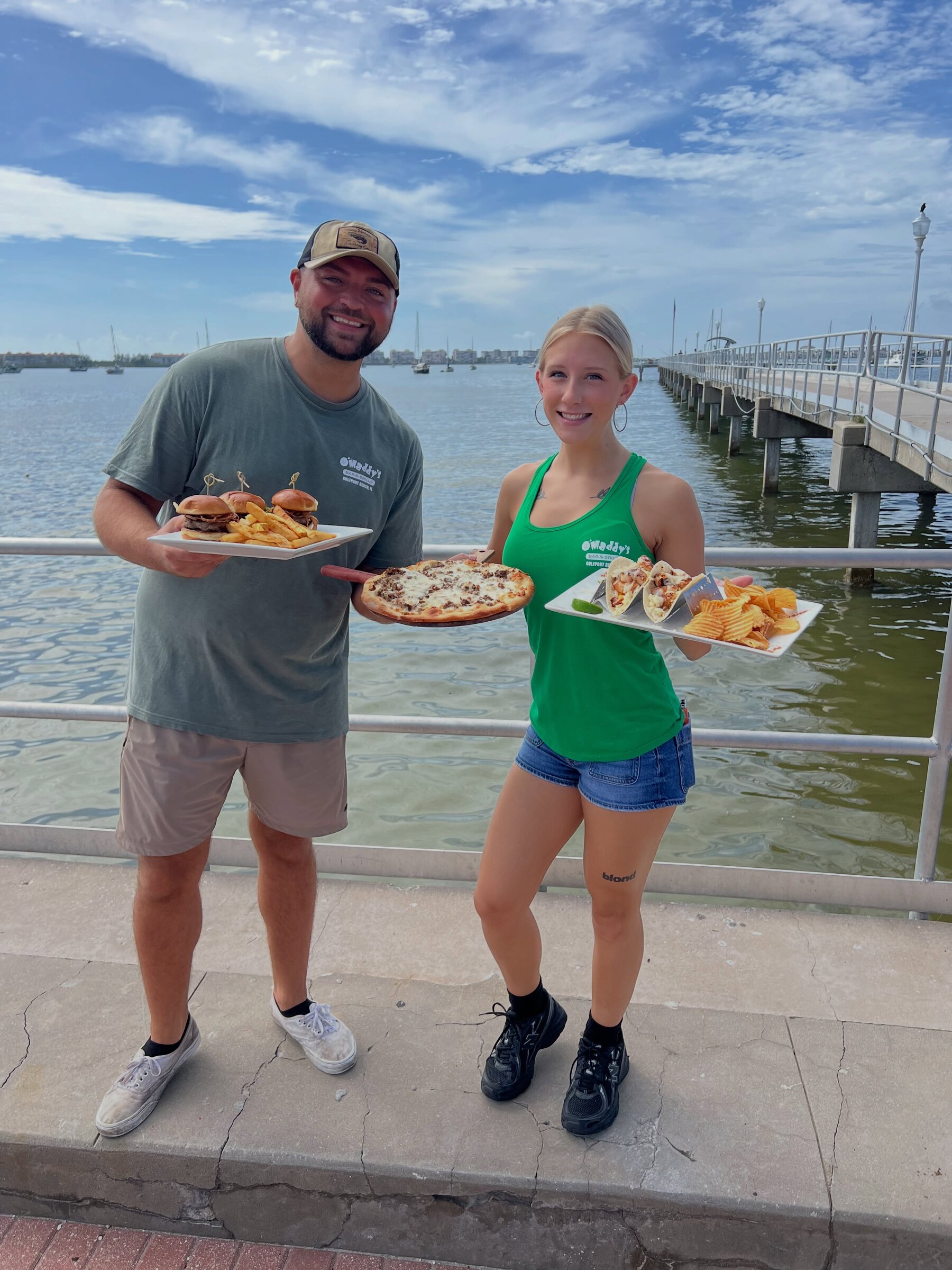 Two O'Maddy's staff holding plates on the Gulfport pier