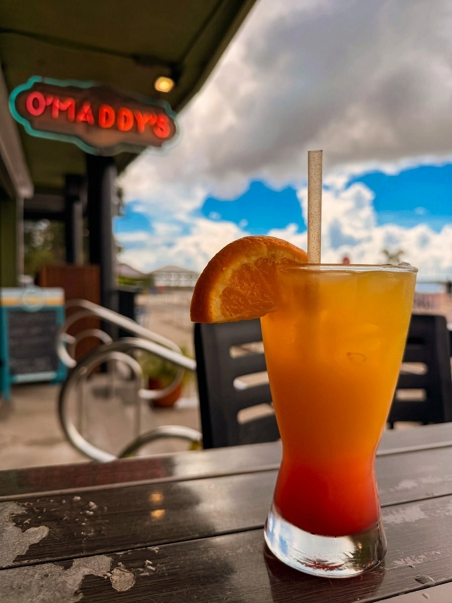 A tequila sunrise on O'Maddy's bar with the neon sign behind