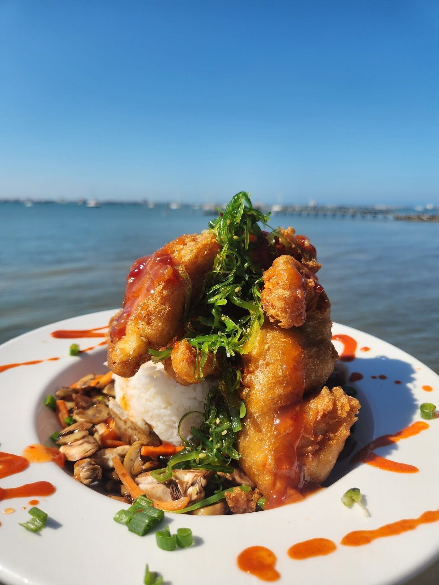 A fried seafood plate under a blue sky over the bay