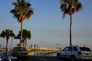Golden-hour view of the Gulfport dock and palm trees beside O'Maddy's on Boca Ciega Bay